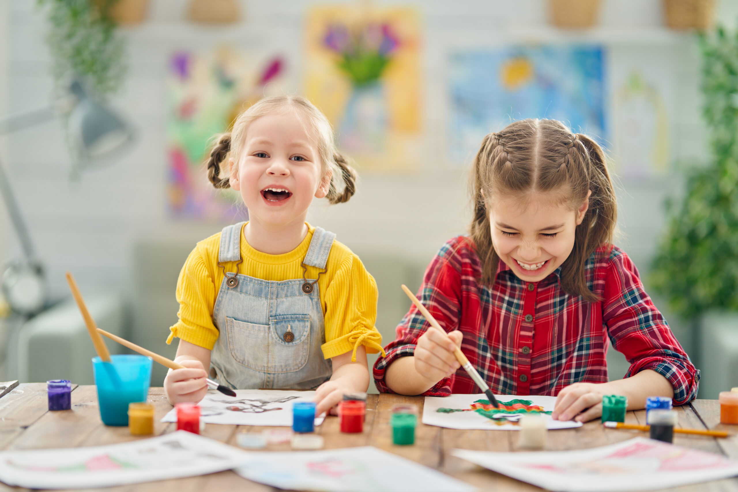 Two young girls paint for art class at home.