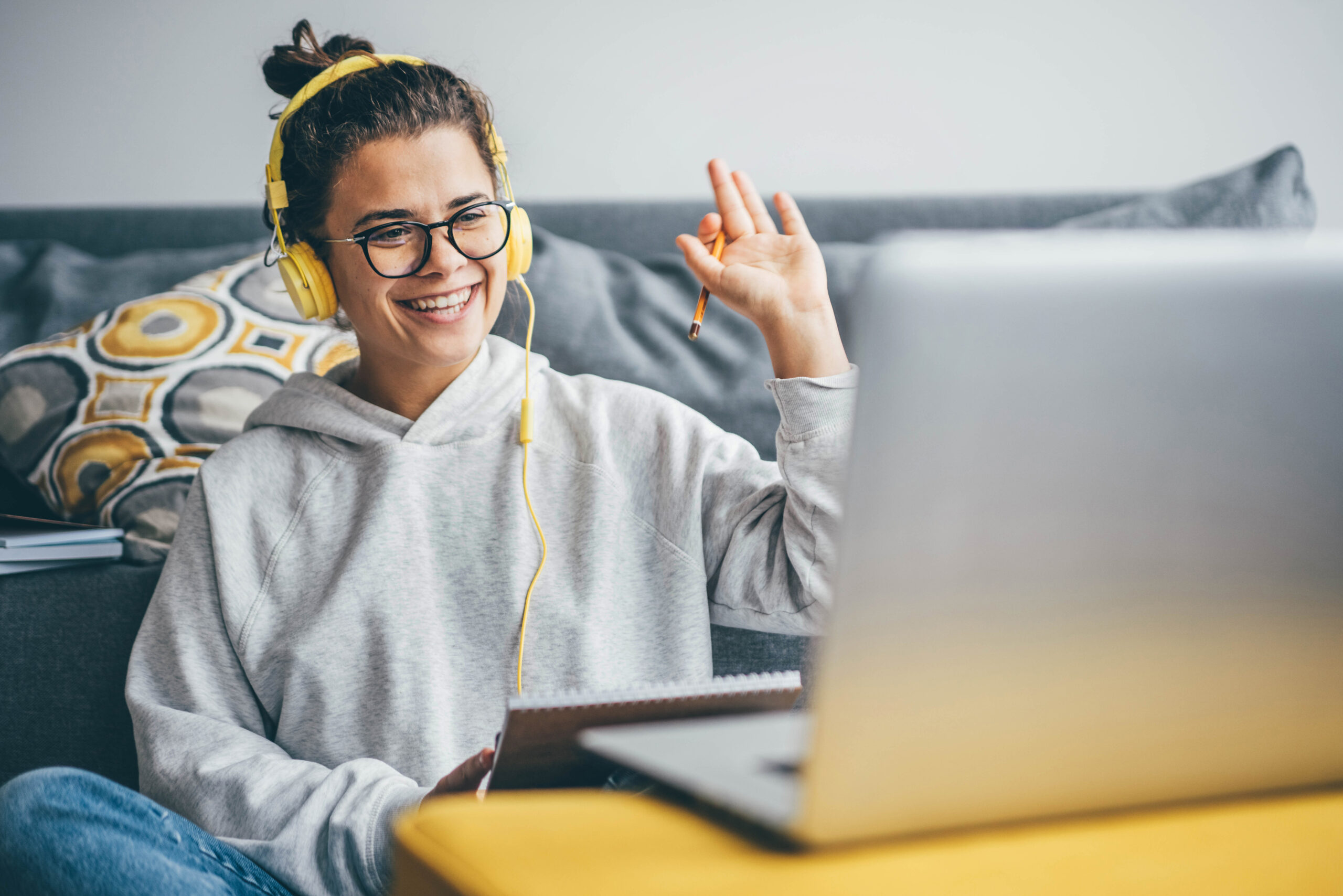 Millennial woman having video call on her computer at home. Smiling girl studying online with teacher.