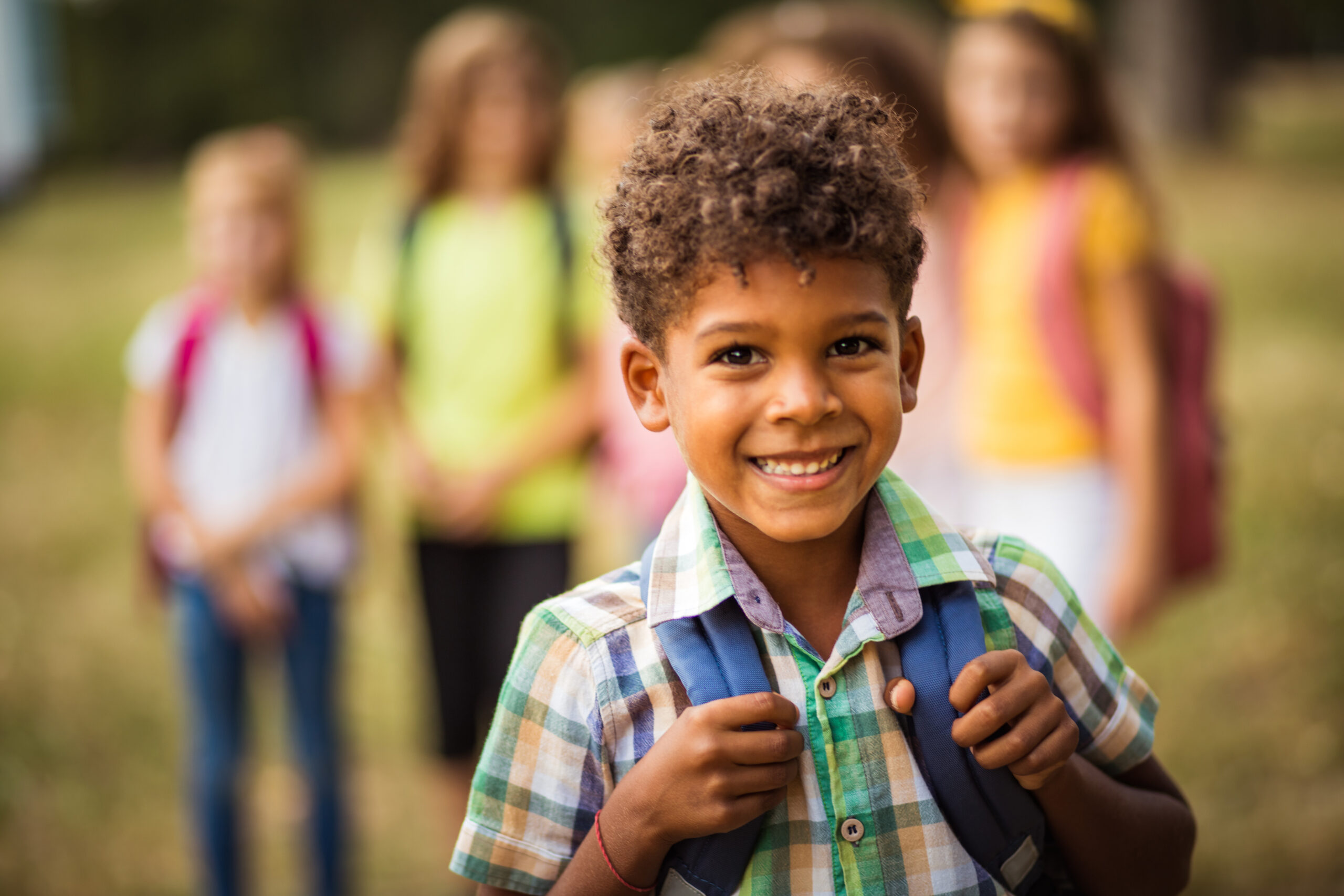 Large group of school kids in nature. Portrait of school boy. Focus is on foreground.