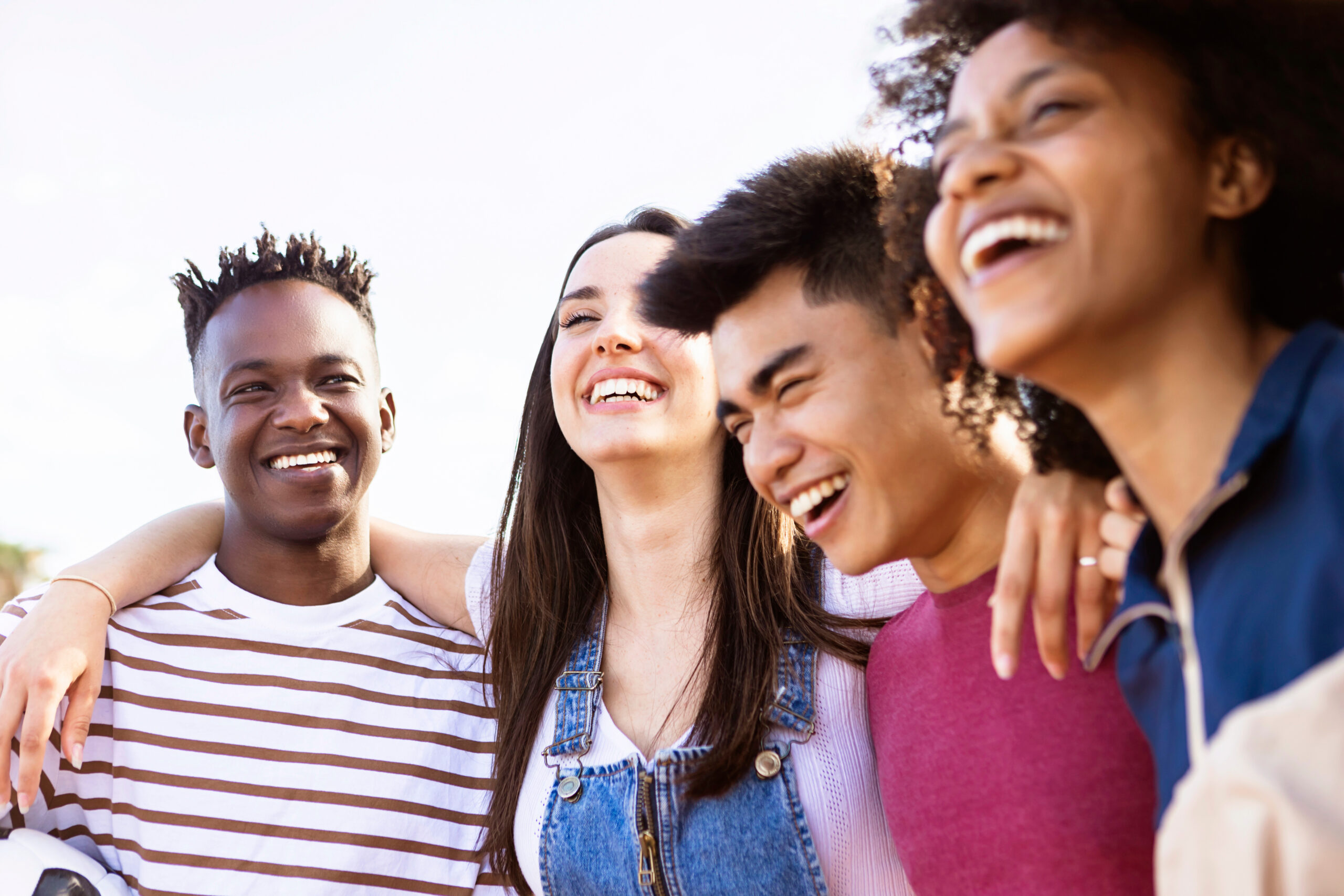 United multiethnic friends laughing and having fun together outdoors - Young adult group of funny people celebrating and hanging out - Summer holidays and college students concept - Focus on african black man