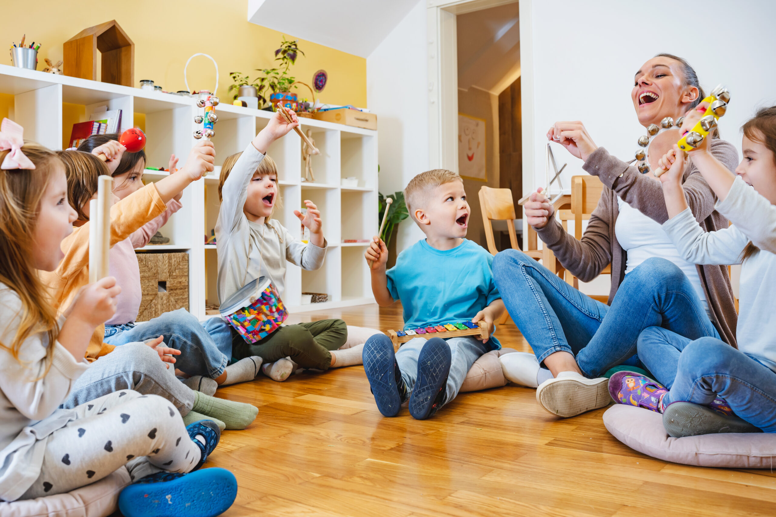 children sitting in a circle with teacher for music class