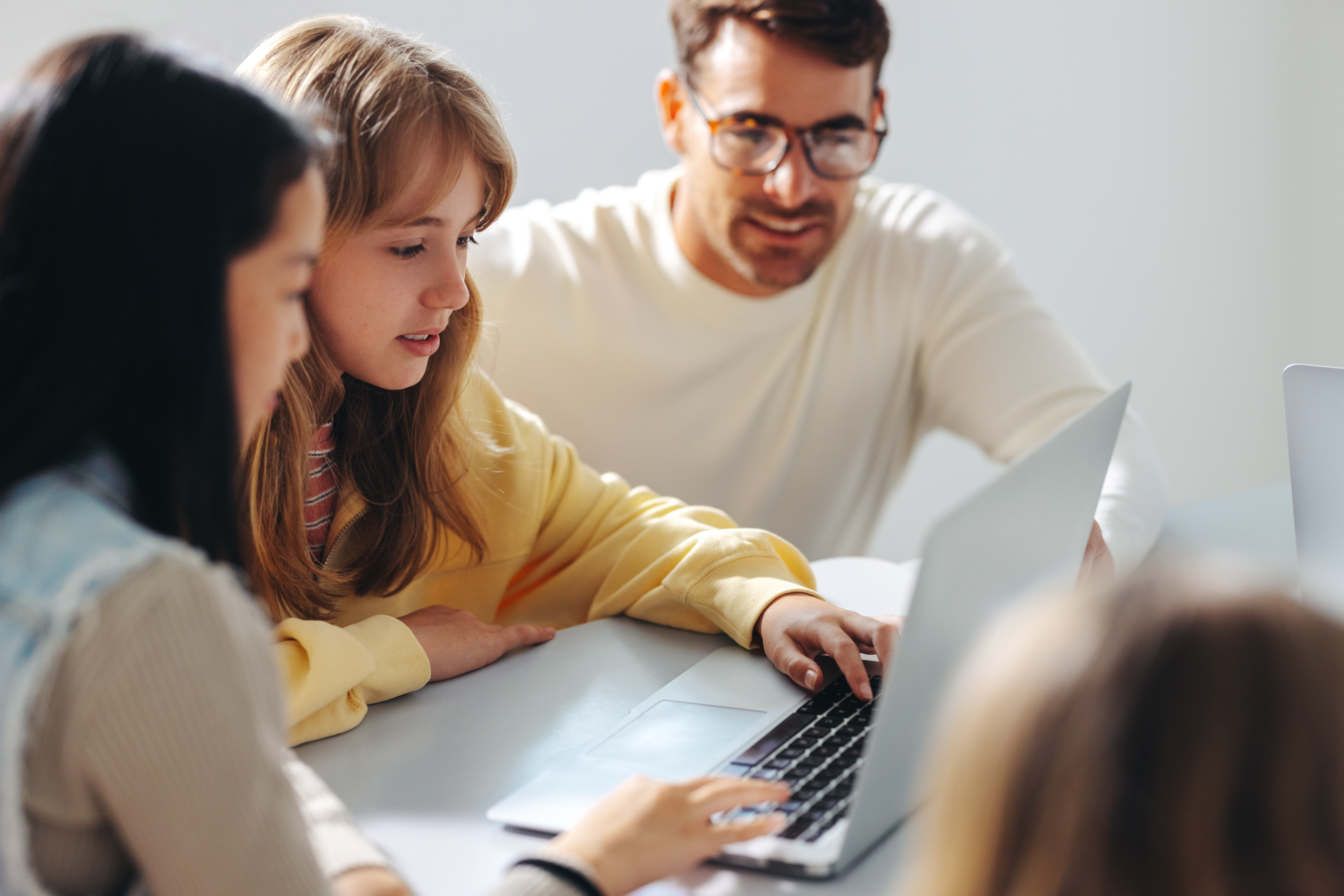 Young girls engaging in a computer class, with a teacher guiding them in a coding lesson. Male educator providing digital education and a strong foundation in computer science for children.