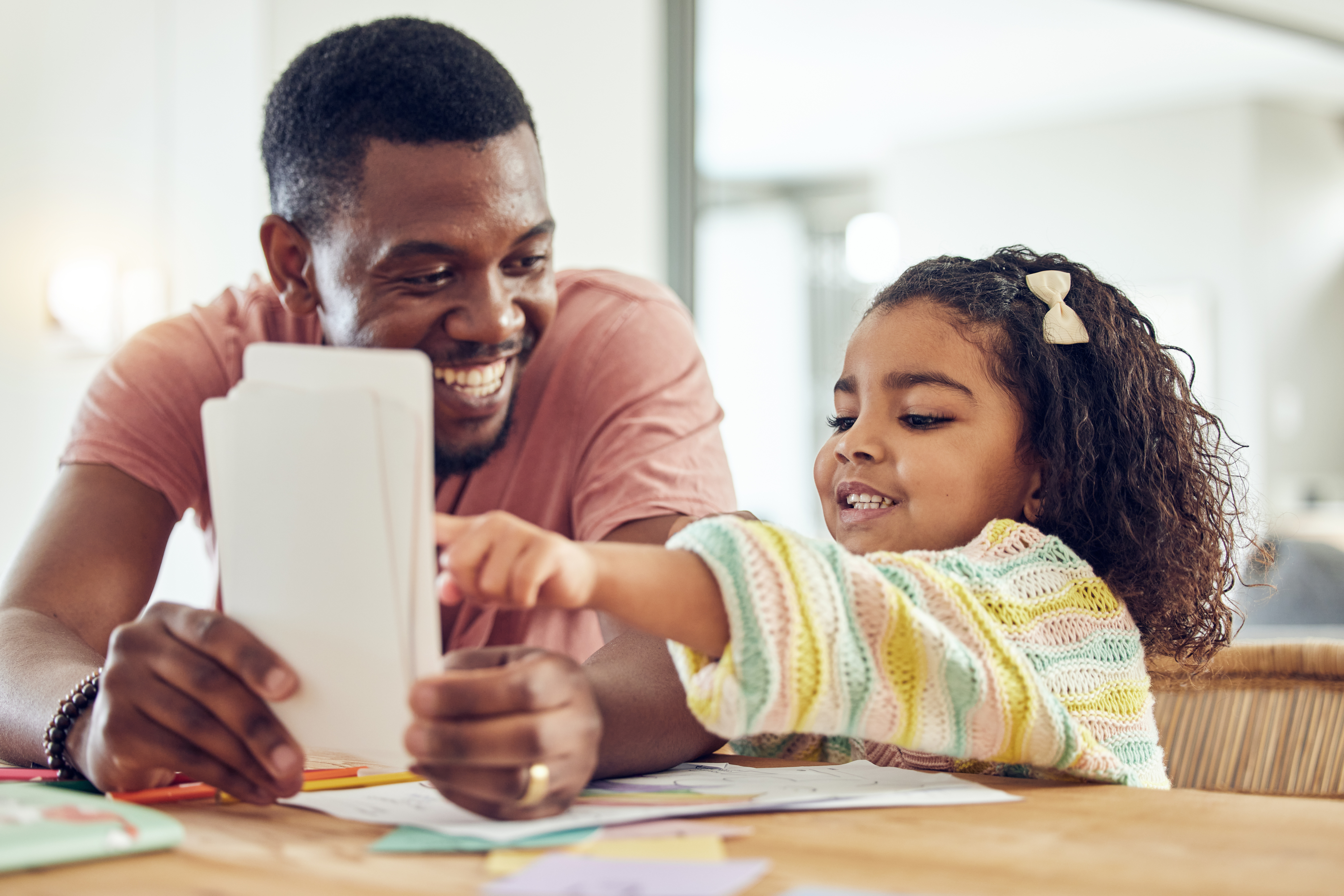 Home school, learning and father helping his child with flash cards, homework or studying. Education, knowledge and African man teaching his young girl kid with reading or an academic assignment