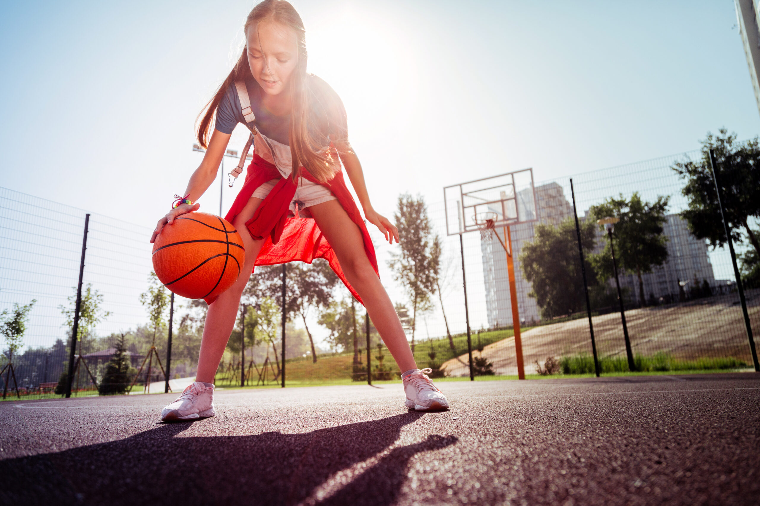 Try to attack. Cheerful kid wearing sneakers while jumping with ball